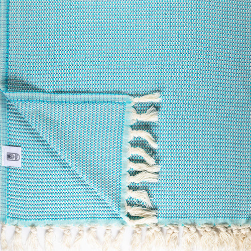 Lightweight Turkish Bath & Home criss cross throw blanket draped over a bed, showcasing its soft fabric and stylish design.
