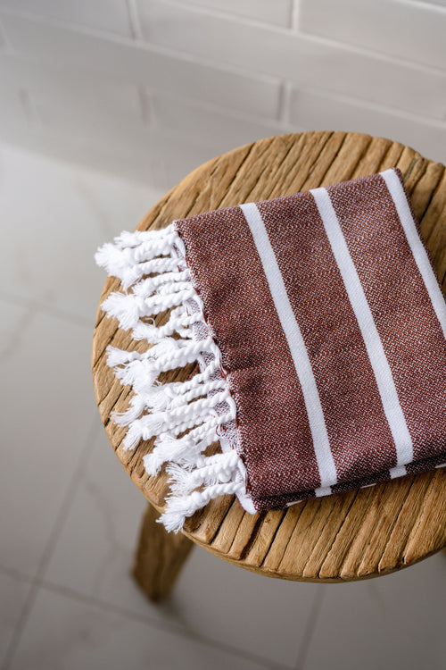 Turkish Bath & Home bold stripe flat weave hand towel showing vibrant striped pattern and soft textured fabric.