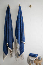 Large thick blue and ecru handwoven towel and small hand towel from Turkish Bath & Home, showcasing textured woven fabric.