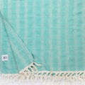 Turkish Bath & Home Bosphorous Wave flat weave bed cover with blue and white wave pattern on a bed.