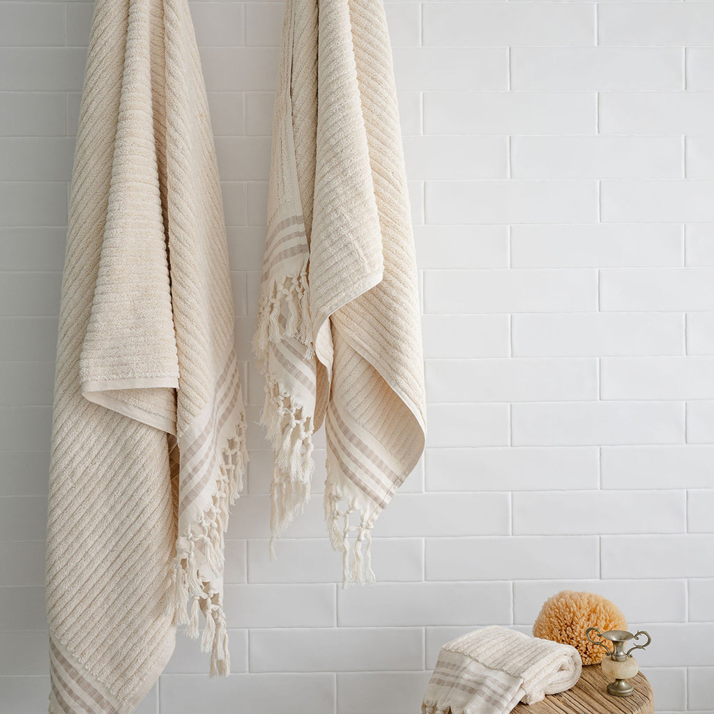 Turkish Bath & Home thick hand towels with ecru stripes, showcasing a luxurious, plush, medium-sized woven towel and matching hand towels.