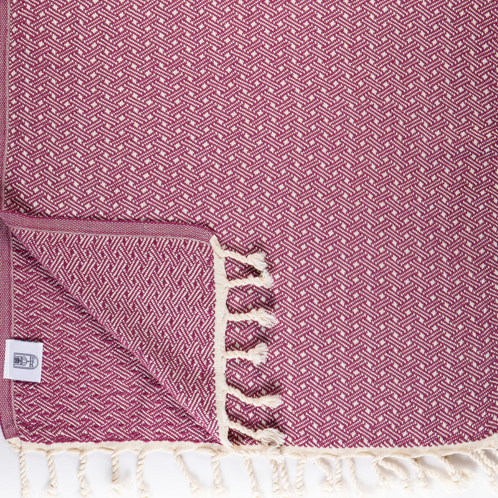 Magnolia patterned towel with white tassels on a matching pink background