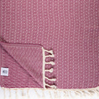 Magnolia patterned towel with white tassels on a matching pink background
